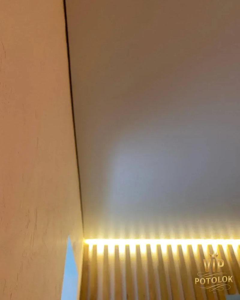 Матова натяжна стеля з прихованою LED-підсвіткою над дерев’яною рейковою стіною